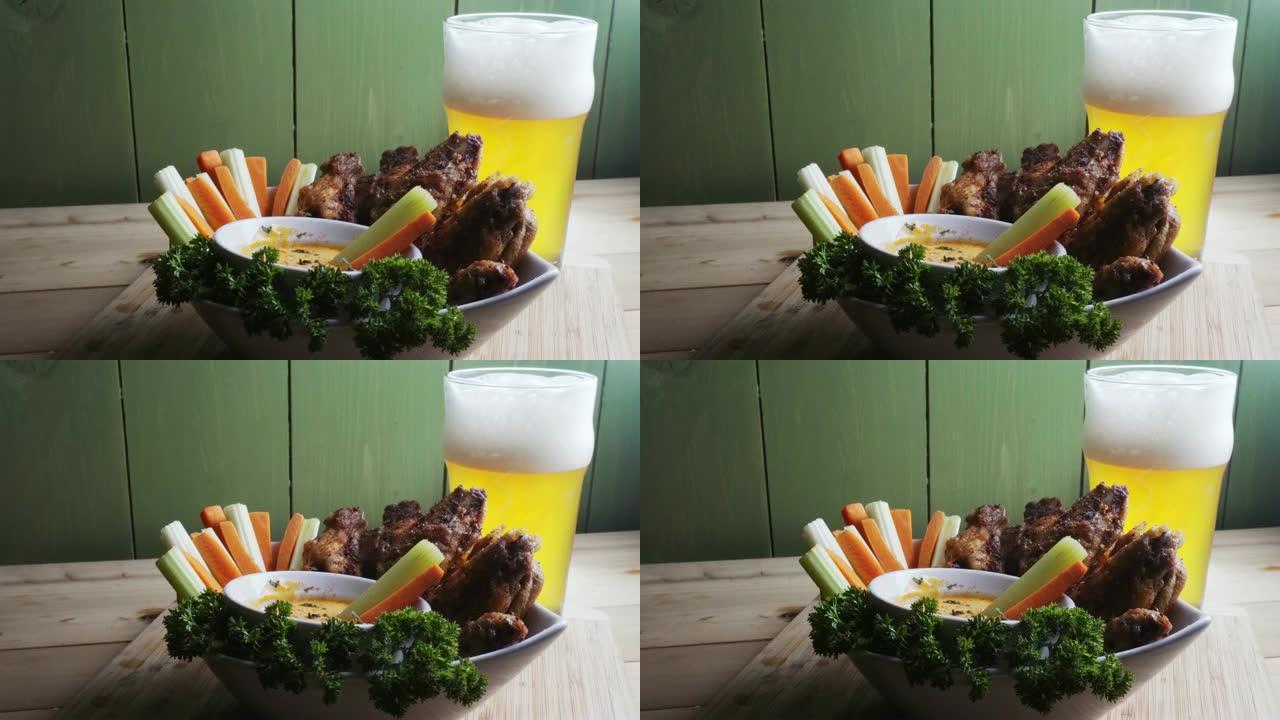 一碗健康的烤鸡翅，配以辣酱芹菜和胡萝卜条，配以啤酒