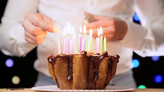 用火柴点燃美丽多彩的生日蜡烛。充满蜡烛的美味巧克力生日蛋糕