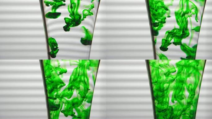 绿色染料溶解在白色背景上的玻璃水中