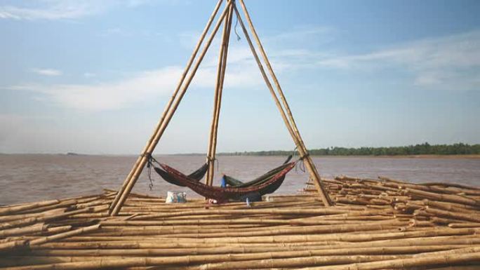 工人的休息场所: 三个吊床绑在竹竿之间，垂直地粘在一堆竹竿中，被拖到河中