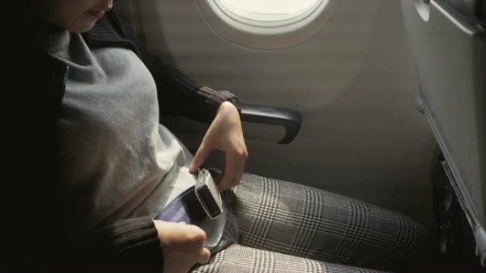 安全概念亚洲女子在飞机上系好安全带准备起飞
