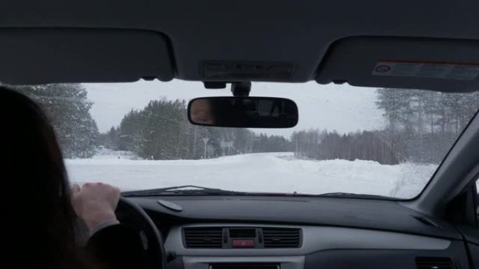 从后座看冬季白天在十字路口和雪路上开车的女人