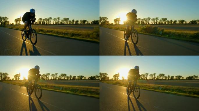 一名骑自行车的人在日落/日出时沿着道路用力兜售。