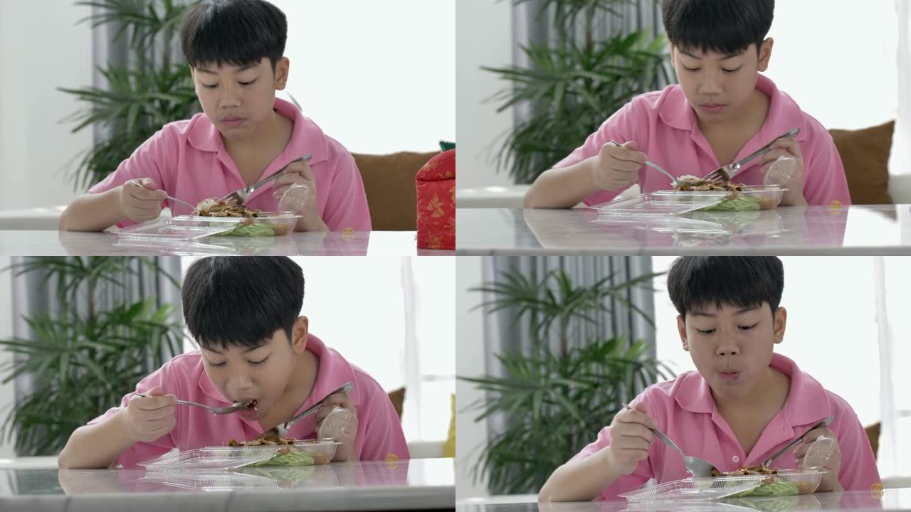 4k亚洲男孩在家吃午餐，午餐吃食物，带茉莉花饭盒的饭盒。