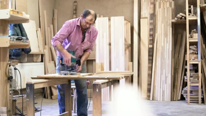 这位65岁的老人安装和调整了电动手动铣床。小型家具厂的木制品。