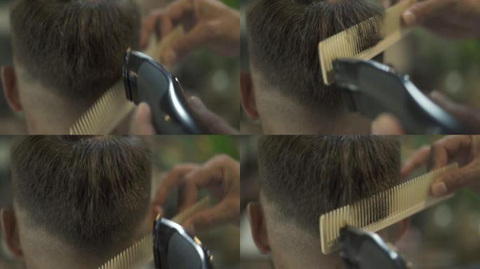理发师在理发店用发发器和梳子理发。理发师在男性沙龙用电动剃须刀做发型。用修剪器和发刷关闭美发