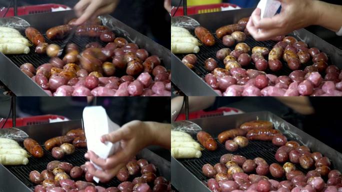 4k女人手的静态镜头使用不锈钢钳子烹饪烤猪肉丸和香肠作为早餐或午餐，在炉子上的铁筛上，在传统市场上的