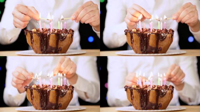 男人用两根火柴点燃生日蜡烛。生日派对，盘子上有美味的巧克力蛋糕，上面有五颜六色的蜡烛