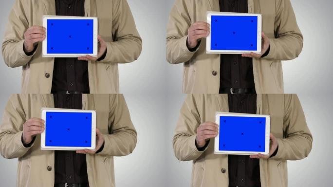 渐变背景上带有蓝屏模型的男性手握平板电脑
