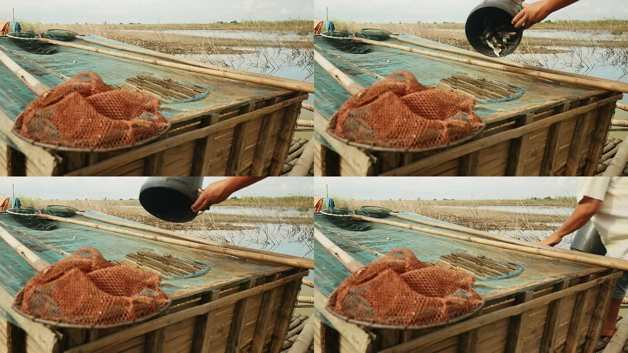 一名渔民将用中国渔网捕获的鱼扔进竹箱的特写镜头