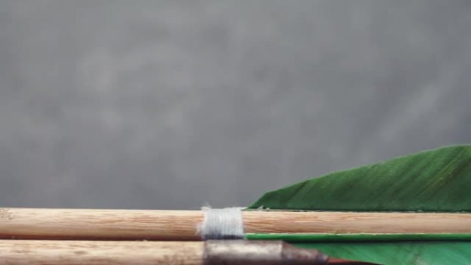 圆形木桌上的旧绿色木箭。美丽的黑暗背景。中世纪手工武器。