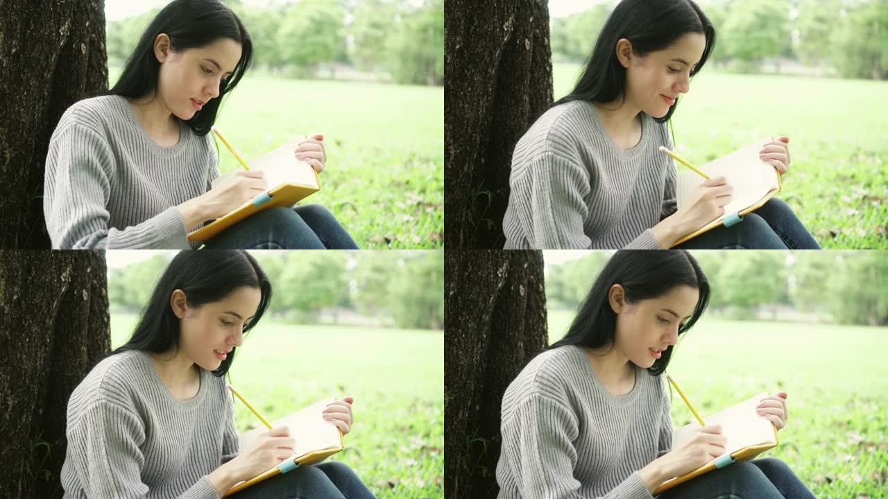 年轻迷人的女人在笔记本上写东西，在公园里微笑