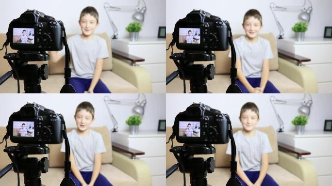 关闭摄像机在三脚架上的视频，一个男孩在液晶屏幕上，模糊的场景在背景上。录制vlog或播客的男性儿童视