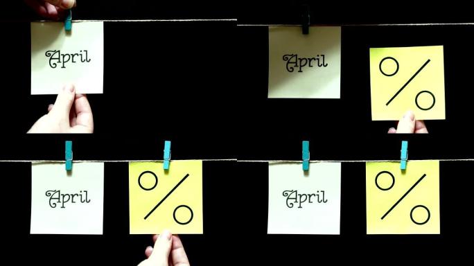 两个彩色贴纸。左边是白色的铭文4月。在右边的黄页上是百分比符号。黑色背景。