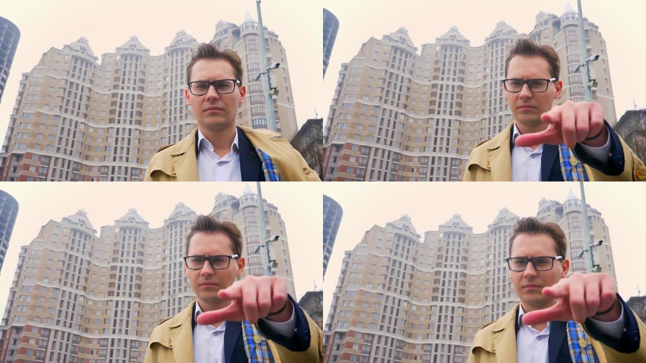 有吸引力的自信的白人男子的特写镜头指出手指，直视相机，背景是现代建筑