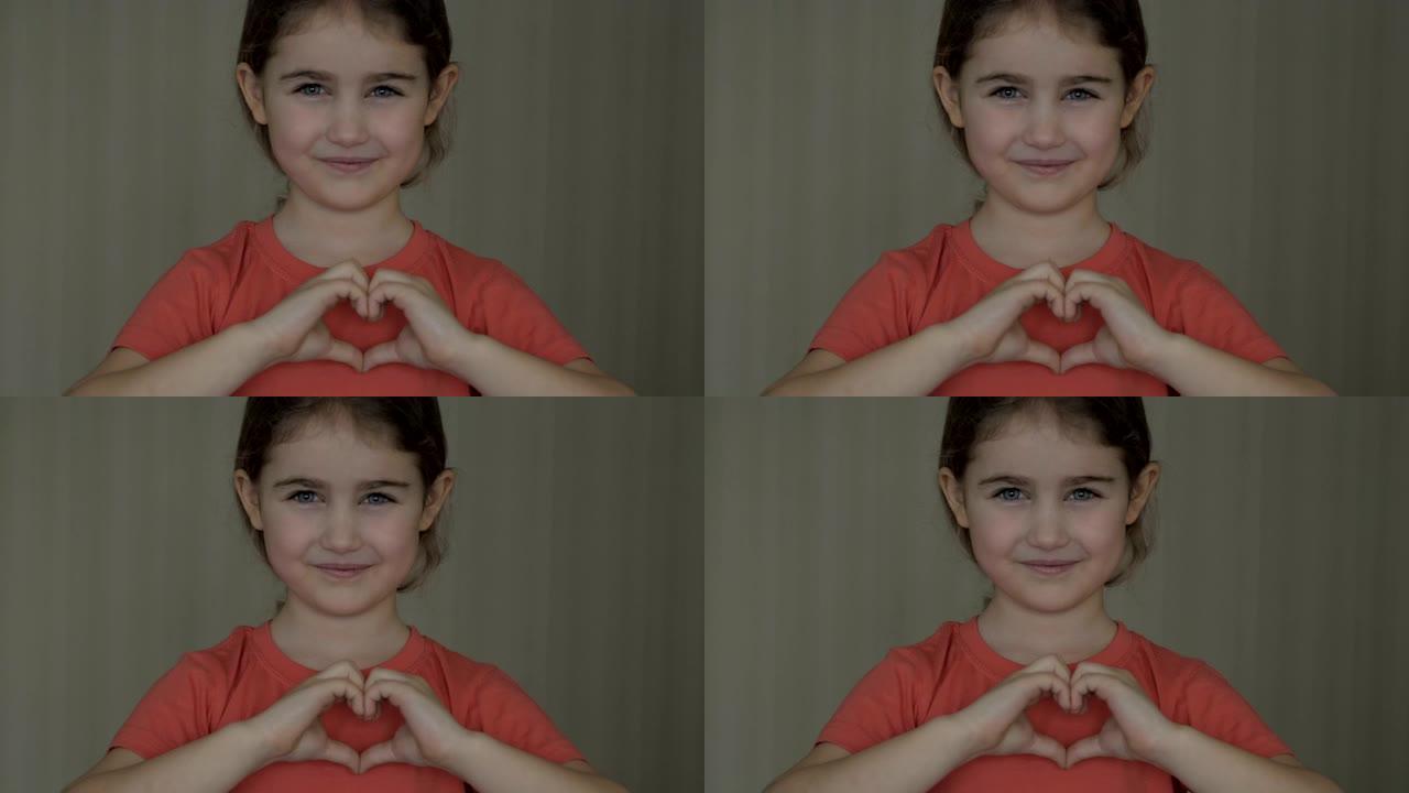 可爱的小女孩用手和微笑着做一颗心。年轻美丽的女孩在爱情中微笑，用手展示心脏的象征和形状。浪漫的概念。