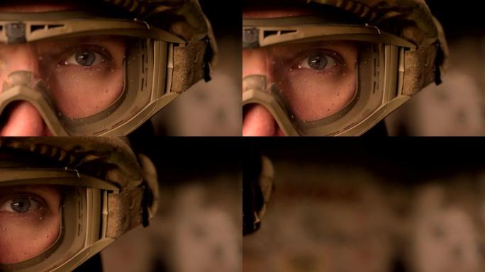 特写聚焦的眼睛强壮的军人穿着制服和头盔，看着摄像机，而站着，真实的现代外观
