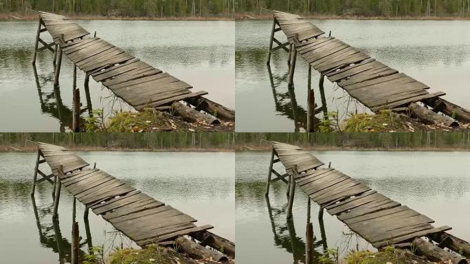 森林湖中破碎的老桥。秋天的白天。光滑的多莉射击。