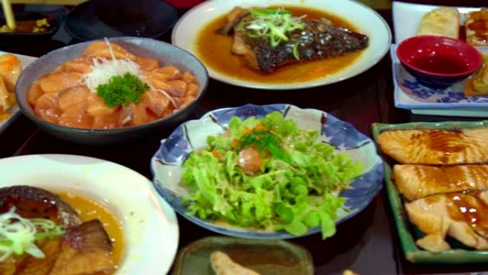 桌上放三文鱼，三文鱼燃烧和烤鸡日本料理。食物的俯视图。