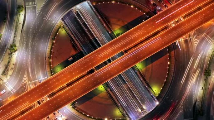 空中俯视道路环形交叉路口在城市夜间与车辆车灯运动。