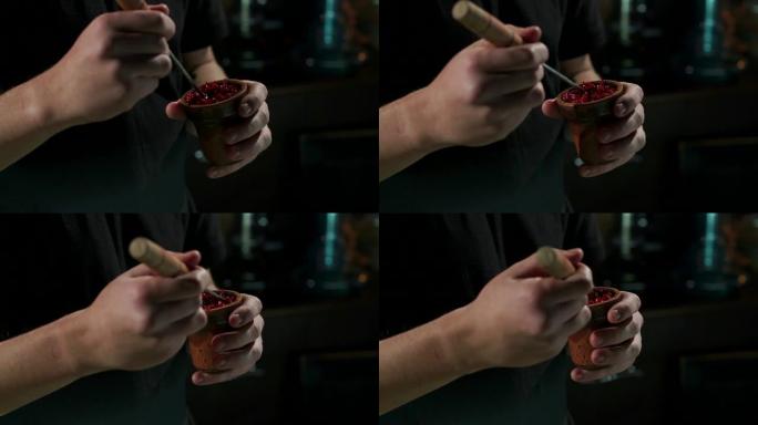准备水烟时，一个人的手将水果烟草放在水烟的碗中。