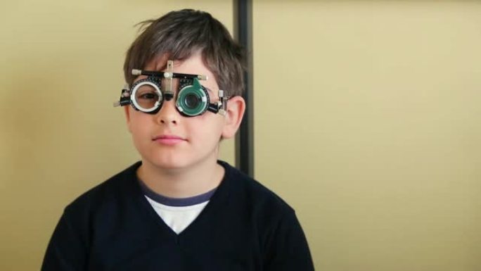 可爱的孩子坐在医生办公室，用试验架确定晶状体，验光师检查视力