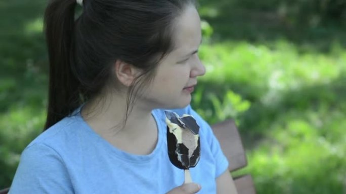 一个女孩坐在公园里吃冰淇淋。