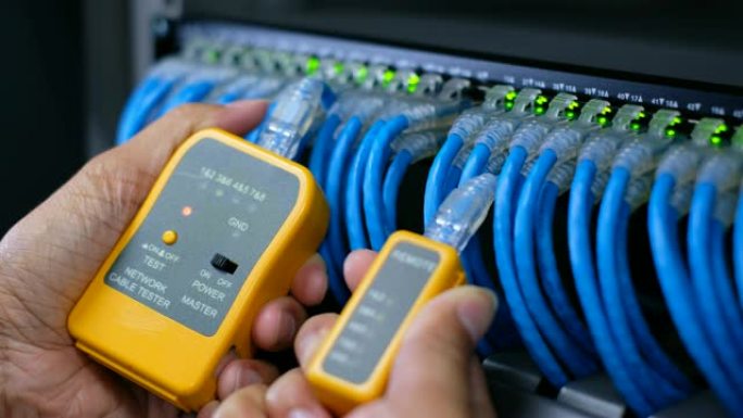 具有测试工具的系统管理员或技术人员，用于测试连接到网络数据中心网络千兆交换机接线板的网络电缆