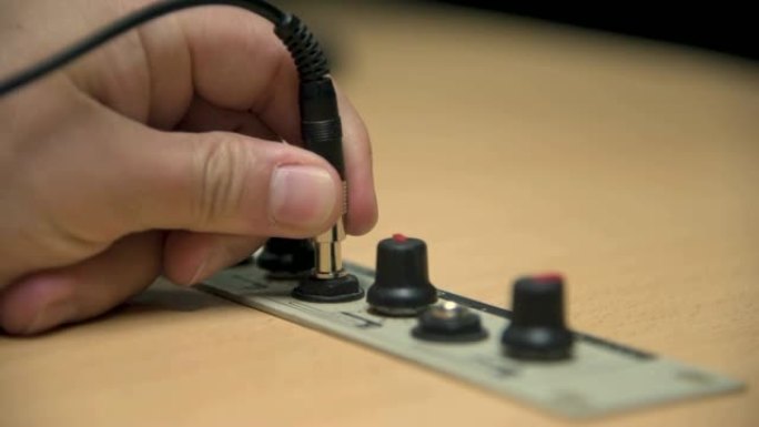 一只手将耳机的插孔插入广播电台的演播室