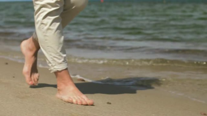 女人的脚赤脚在夏日海滩上行走