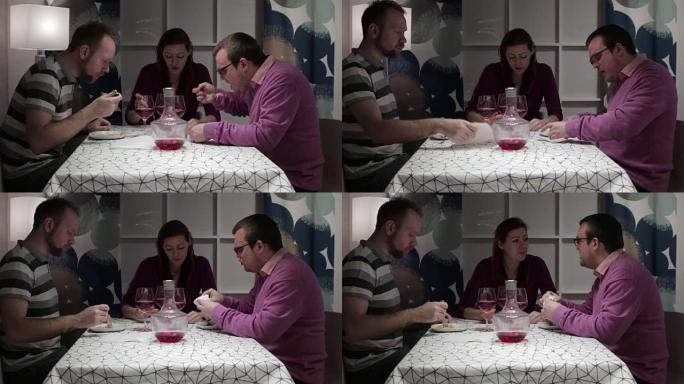男人和女人坐在餐桌旁吃饭和说话