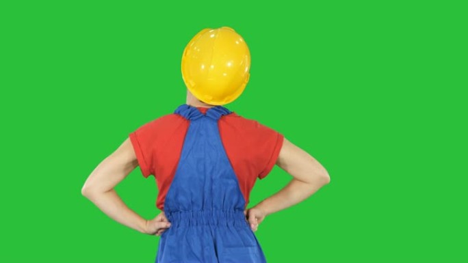 双手叉腰的女建筑工人看着绿色屏幕上的东西，色度键