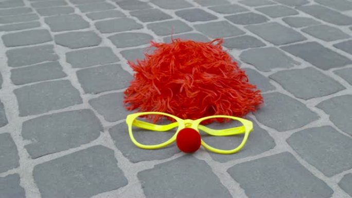有趣的假发，伪装的眼镜和铺砌地面上的泡沫材料鼻子-狂欢节概念或庆祝概念
