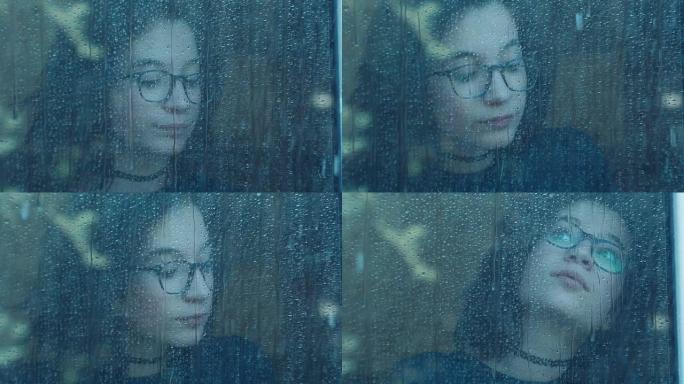 雨天窗户后面无聊的女孩。慢动作拍摄