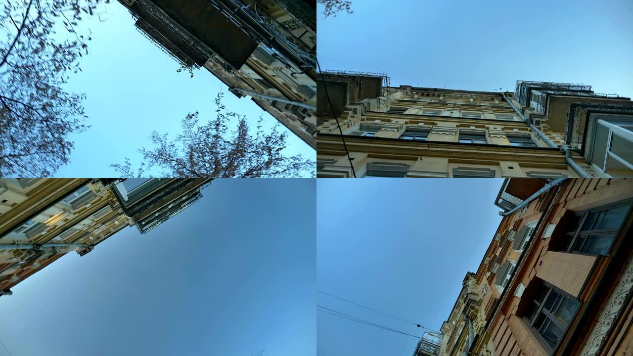 在蓝天背景上从城市建筑物和树木的底部旋转。