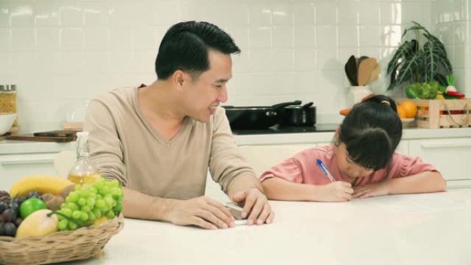 父亲用数字平板电脑教女儿在现代厨房做作业