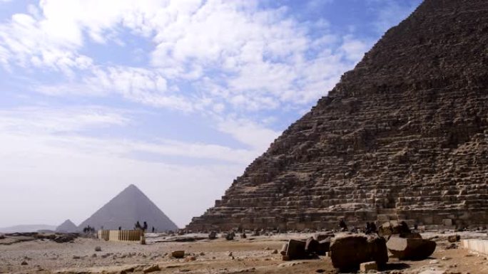 埃及吉萨金字塔的美丽景色。我们可以看到云朵在联合国教科文组织分类的纪念碑上方，埃及人在金字塔前行走。