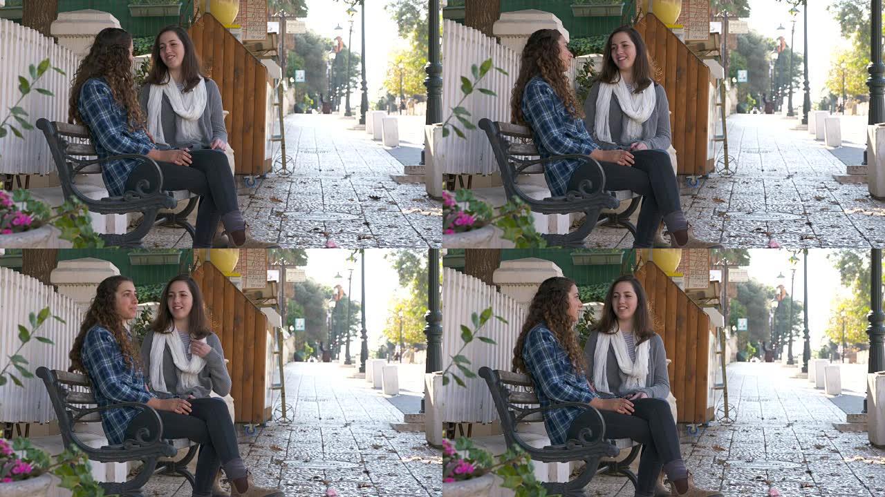 两个十几岁的女孩走路和坐在长凳上