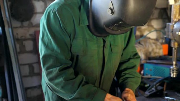 机械师在修理厂用工具工作。穿着工作服的人在车库或车间工作。为了安全，盖伊戴着防护面具。努力工作的理念