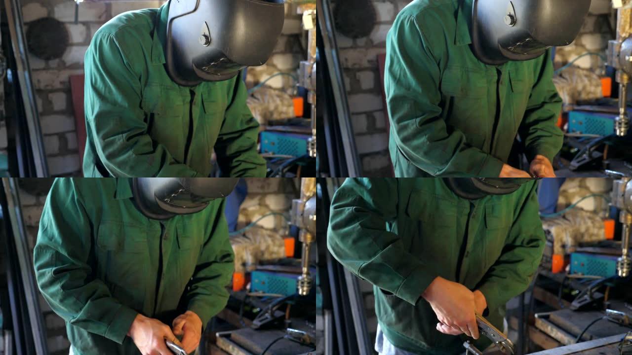 机械师在修理厂用工具工作。穿着工作服的人在车库或车间工作。为了安全，盖伊戴着防护面具。努力工作的理念