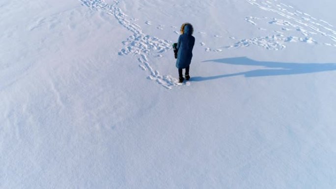 妈妈和儿子在白雪覆盖的地方玩耍。航拍镜头，摄像机在旋转。冬天的家庭消遣。