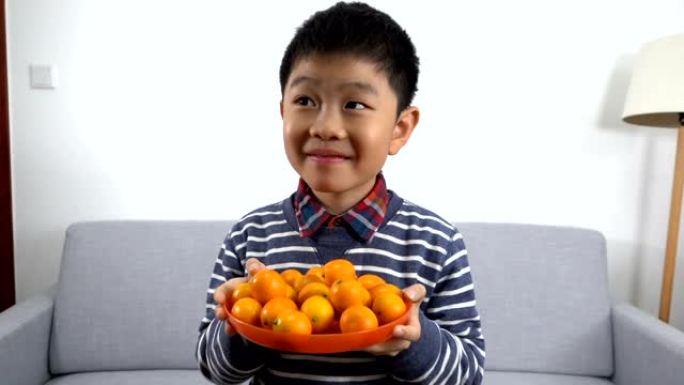 亚洲男孩举起一碗金橘