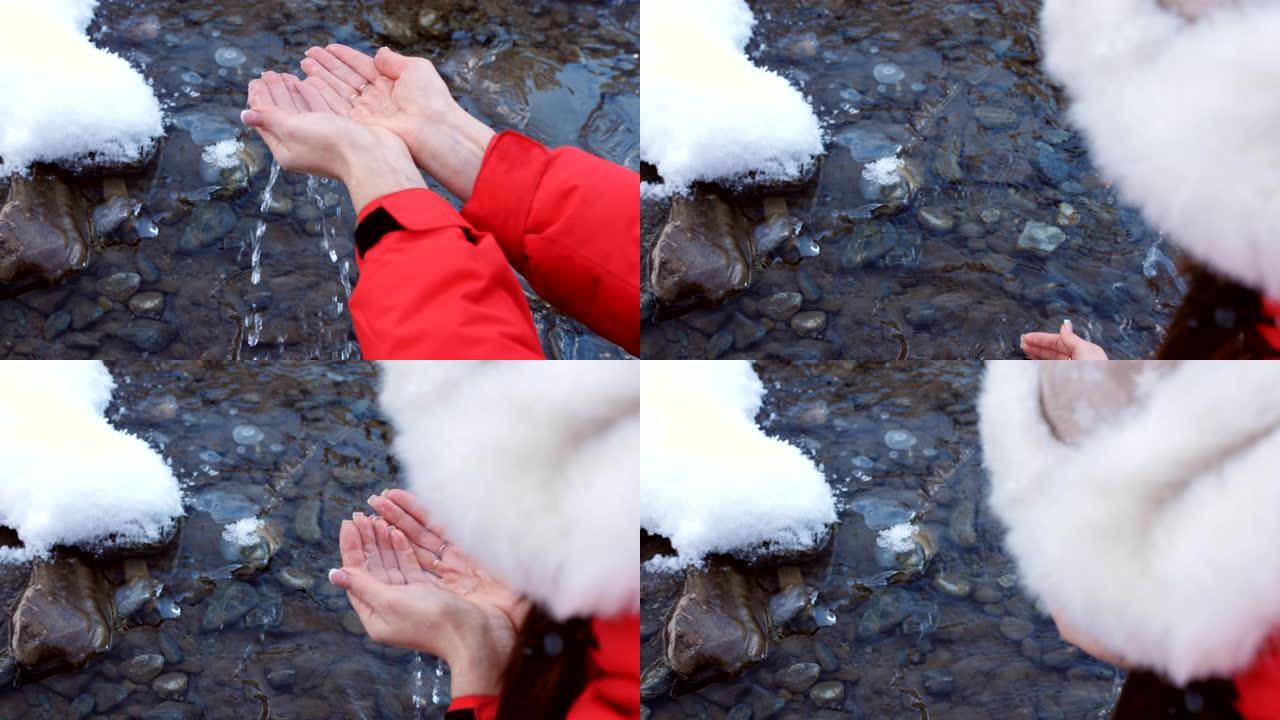 女人在冬天的特写镜头正从山上的河水和饮料中获得干净，清澈的水。
