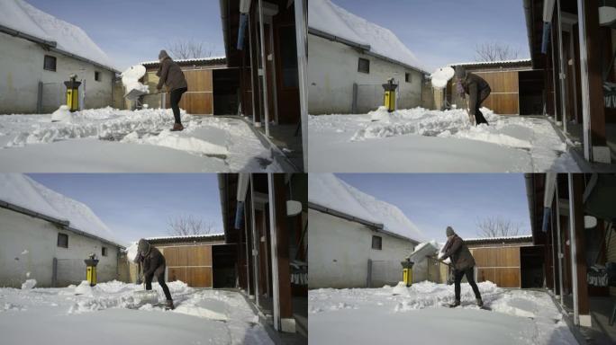 男子在院子里铲新雪