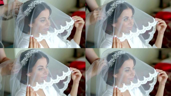 美丽的女人正在为婚礼做准备，拿着面纱，面带微笑。