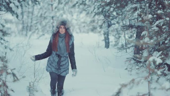 美丽的女孩走过森林里的漂泊。美丽的风景，白雪皑皑的树木。