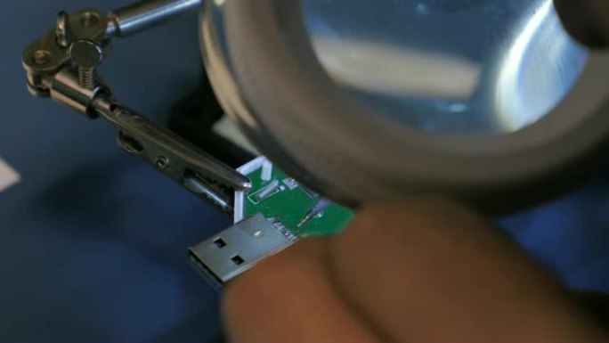 特写一个人在USB设备上焊接引脚的镜头