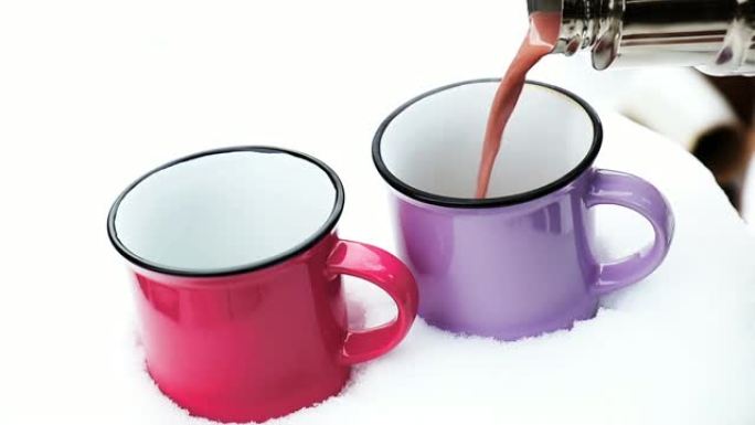把热巧克力倒在杯子里。热巧克力搭配粉红色和紫色的棉花糖两个杯子，包裹在舒适的冬季粉红色围巾上，放在花