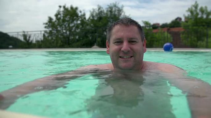泳池里的男人对着镜头微笑。