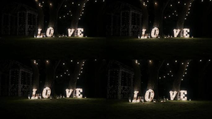 带灯泡灯的木制字母。字-爱。舞台上照亮了爱这个词。由光滑地板上的灯组成的爱字